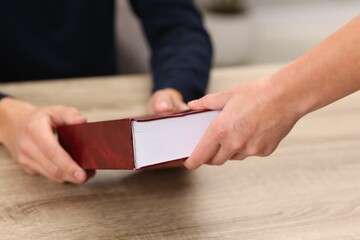 Writer signing book for reader at wooden table, closeup