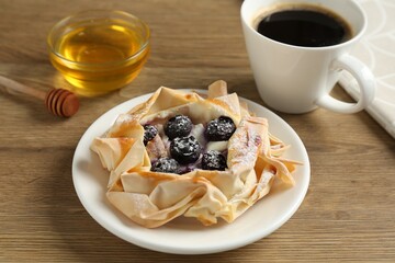 Tasty puff pastry with blueberries, honey and coffee on wooden table, closeup