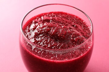 Fresh beetroot smoothie in glass on pink background, closeup