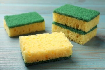 Soft sponges on light blue wooden table, closeup