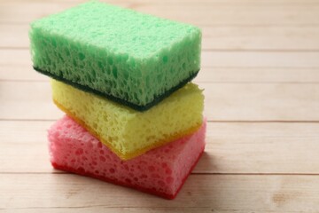 Soft sponges on wooden table, closeup. Space for text