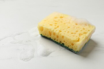 Yellow sponge with foam on white background, space for text