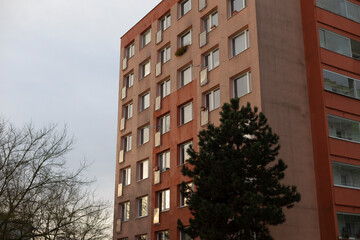 A very tall building featuring an abundance of windows, situated prominently with a beautiful tree located right in front of it