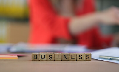 A creative business concept showcased in an office setting, featuring scrabble tiles that spell BUSINESS