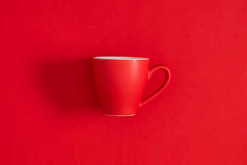 Red cup on red background. Monochrome minimal background. Top view, flat lay.