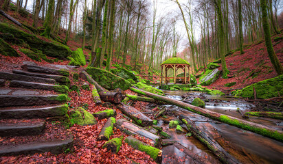 Stone steps lead to a charming gazebo nestled in a mossy forest