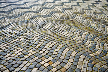 Fototapeta premium Textured cobblestone pavement with a wavy pattern showcasing various colors and shapes.