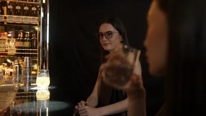 Focusing on beautiful woman in soda drink accompanied by friends at luxurious bar nightclub. Smart bartender providing excellent service beverage menu at vibrant nightlife party atmosphere. Vinosity.