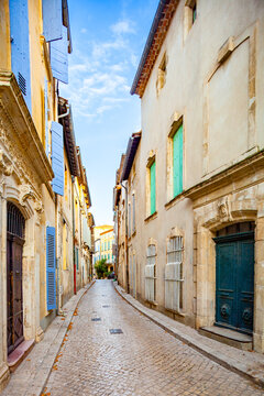 Fototapeta TARASCON, FRANCE: historic center, narrow pedestrian cobbled street,  lined with traditional houses and multicolor window shutters