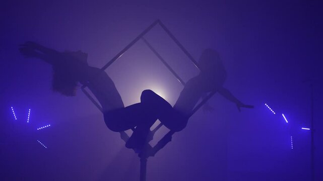 Two Acrobats Performing Tricks Together Inside a Cube