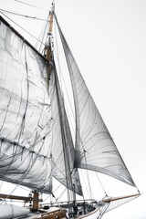Obraz premium A large sailboat with white sails on a calm body of water, perfect for a serene day out or as a background for travel or adventure-themed projects