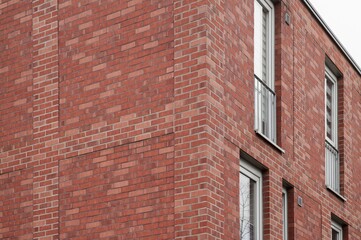 Modern red brick building facade with windows and balconies showing urban lifestyle