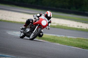 Fototapeta premium Motorcycle rider riding on a classic red sport bike through a corner.