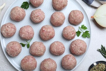 Many fresh raw meatballs on white table, flat lay