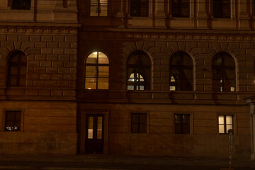 A large building featuring numerous windows is beautifully illuminated during the night hours,...