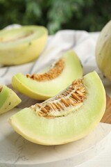 Fresh cut honeydew melon on white wooden table, closeup