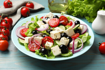 Delicious salad with feta cheese served on blue wooden table, closeup