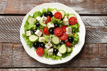Delicious salad with feta cheese on wooden table, top view