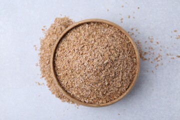 Buckwheat bran in bowl on light grey table, top view