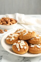 Tasty cookies with almond flakes and nuts on white marble table, closeup