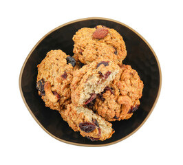 Delicious oatmeal cookies with dried cranberries and nuts in bowl isolated on white, top view