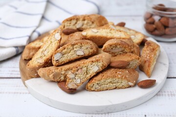 Tasty almond biscuits (Cantuccini) and nuts on white wooden table, closeup
