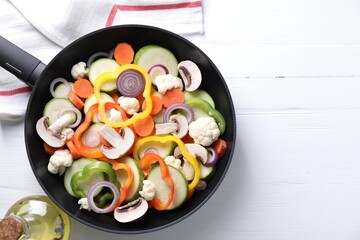 Frying pan with mix of vegetables and mushrooms on white wooden table, top view. Space for text