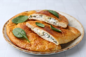 Tasty calzones with basil and cheese on white table, closeup