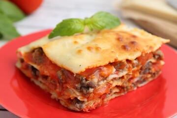Piece of delicious cooked lasagna with basil on table, closeup