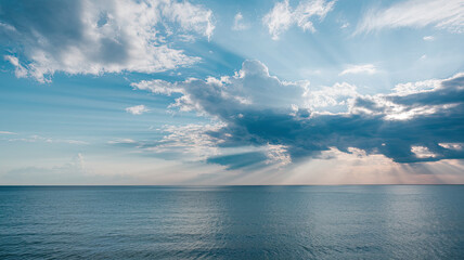 Vast Calm Blue Ocean with Dramatic Sky, Fluffy White Clouds and Sunlight Rays Illuminating Water, Horizon Faintly Visible, Serene