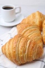 Tasty fresh croissants and cup of coffee on white marble table, closeup