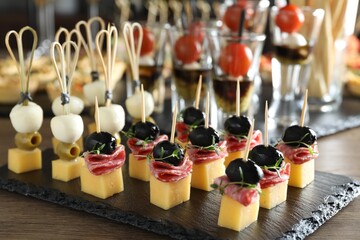 Many different tasty canapes on wooden table, closeup