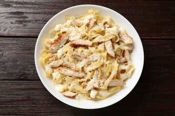 Tasty Alfredo pasta with chicken on wooden table, top view