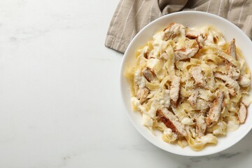 Tasty Alfredo pasta with chicken on white marble table, top view. Space for text