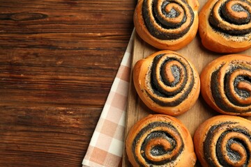 Tasty buns with poppy seeds on wooden table, top view. Space for text