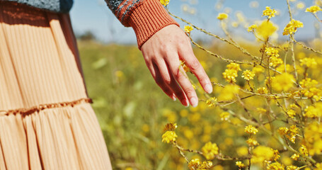 Woman, hand and touch flowers at field on holiday, vacation and tourist relax outdoor. Travel, fingers and person with plants in garden, countryside or back on adventure for freedom in nature closeup