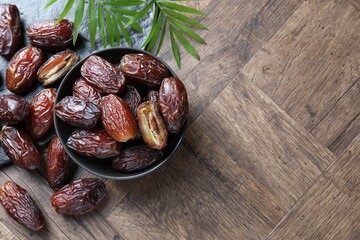 Tasty dried dates and leaves on wooden table, flat lay. Space for text