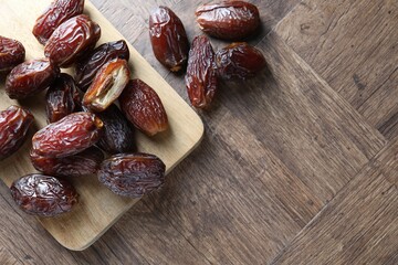 Many tasty dried dates on wooden table, top view. Space for text