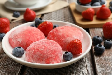 Delicious mochi, strawberries and blueberries on wooden table, closeup