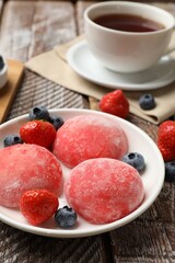 Delicious mochi, strawberries, blueberries and tea on wooden table, closeup
