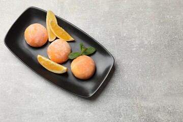 Tasty mochi, cut orange and mint on grey textured table, top view. Space for text