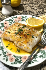 Elegant Baked White Fish Fillet with Lemon Garnish on Decorative Plate for Culinary and Food Photography Themes