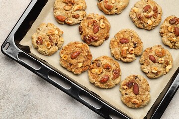 Tasty cookies with nuts in baking tray on gray textured table, top view