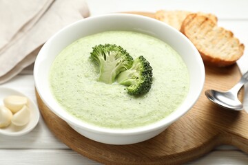 Delicious broccoli cream soup served on white wooden table, closeup