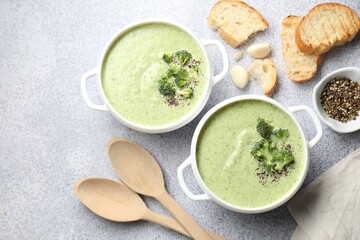 Delicious broccoli cream soup served on light table, flat lay