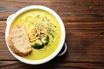 Delicious broccoli cream soup and crouton in bowl on wooden table, top view. Space for text