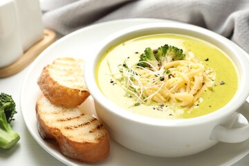 Delicious broccoli cream soup served on white table, closeup