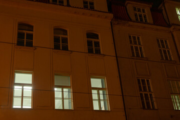 An impressive building adorned with numerous windows is beautifully illuminated during the nighttime hours, creating a captivating scene