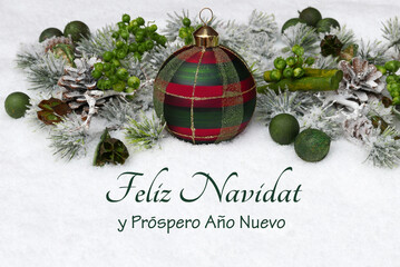 Tarjeta navideña: bolas navideñas con ramas de abeto en la nieve y la inscripción en español...