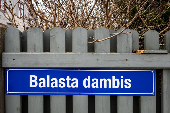 Riga, Latvia  A road sign on Balasta Dambis on a picket fence, a fancy neighbourhood on Kipsala Island.